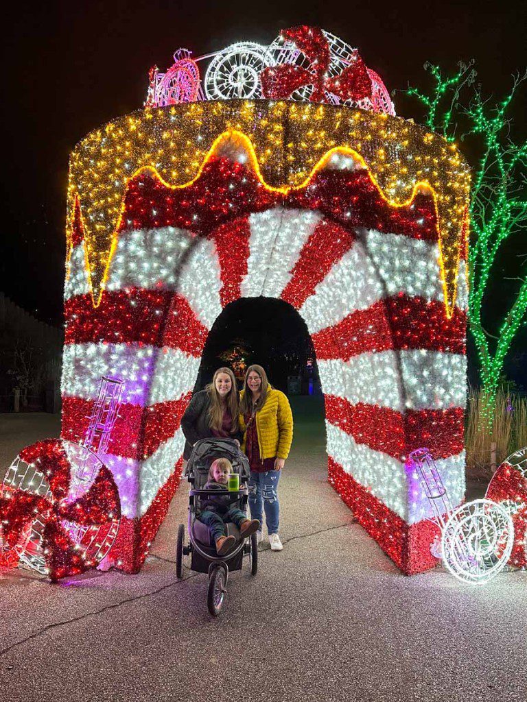 Two women and a baby inside a candy cane lighting display